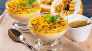 Receita de mousse de maracujá: taças com mousse e a fruta cortada ao lado.