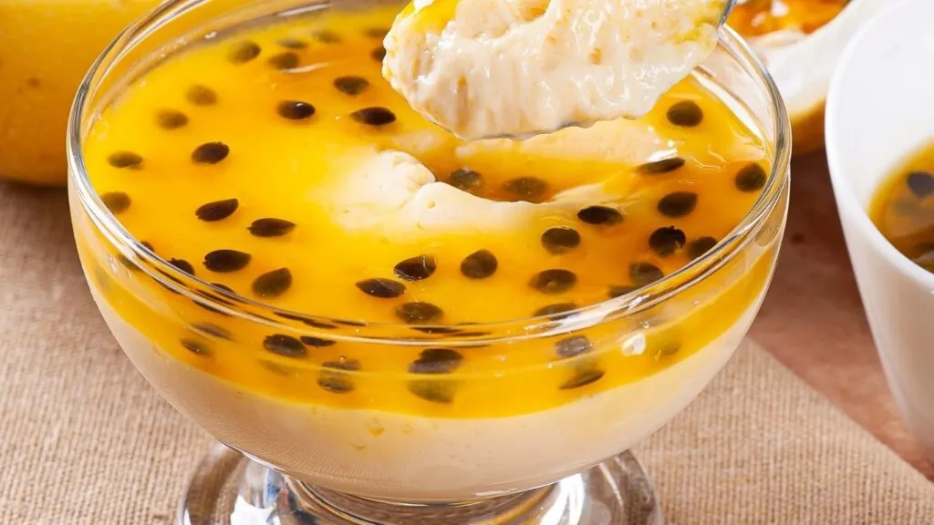 Receita de mousse de maracujá: taça com mousse de maracujá e colher cheia já pegando o doce.